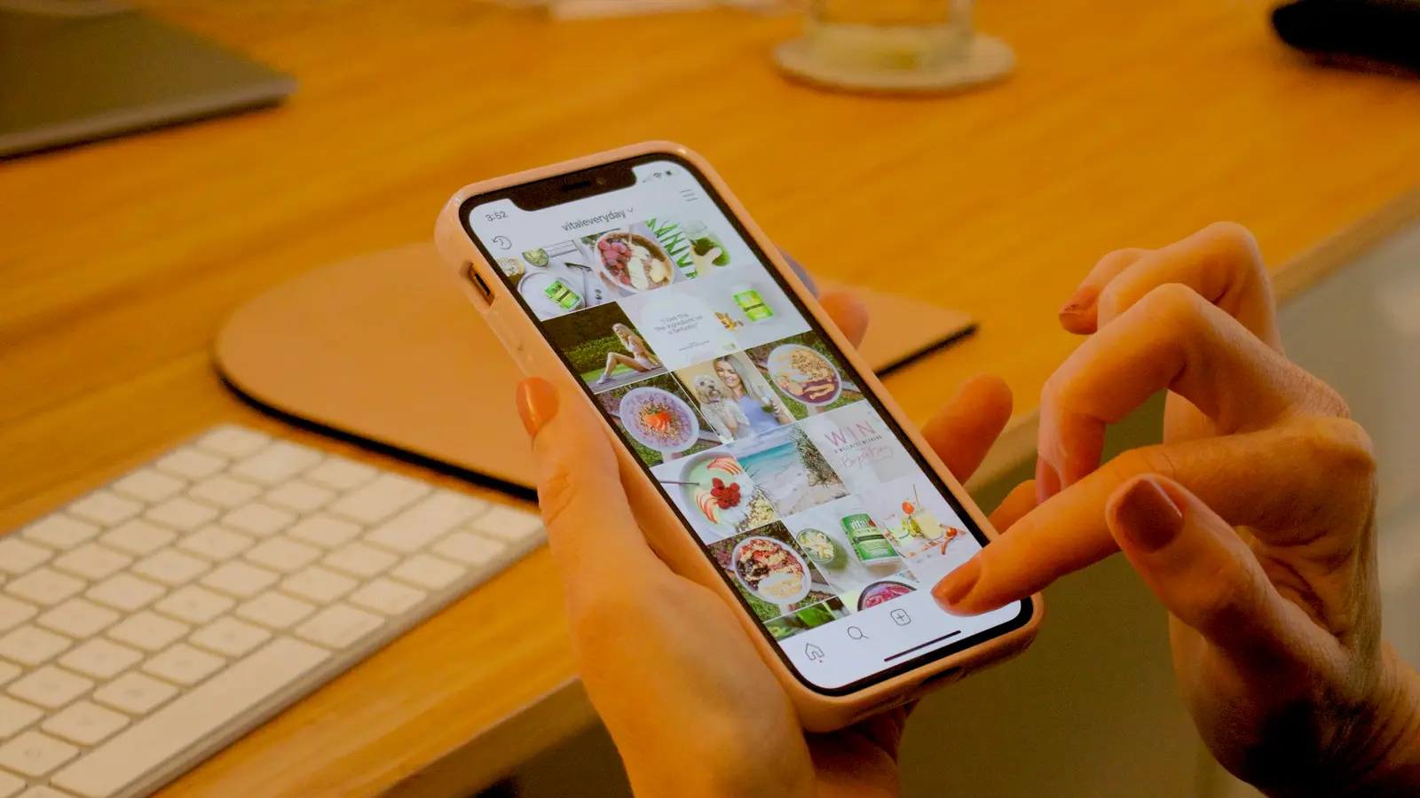 Manos usando Instagram en un celular sobre un escritorio