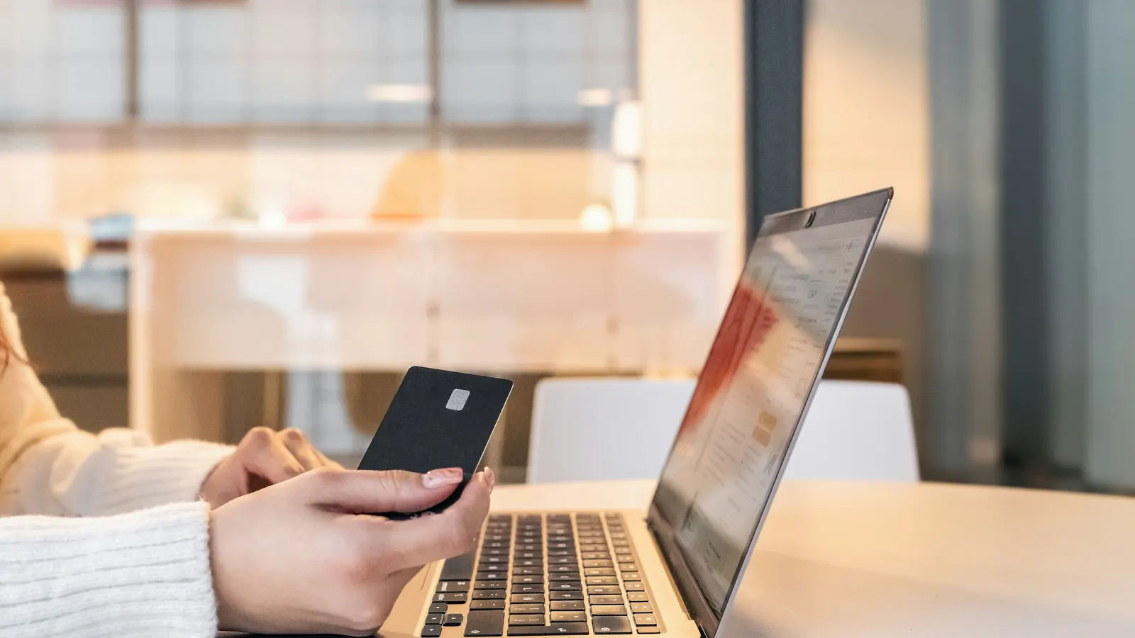 Persona con una tarjeta en la mano comprando online desde una notebook
